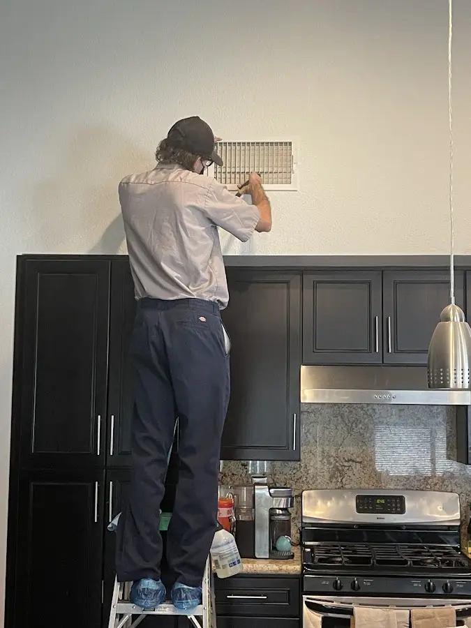 Technician inspecting an air vent during HVAC service in Hudson